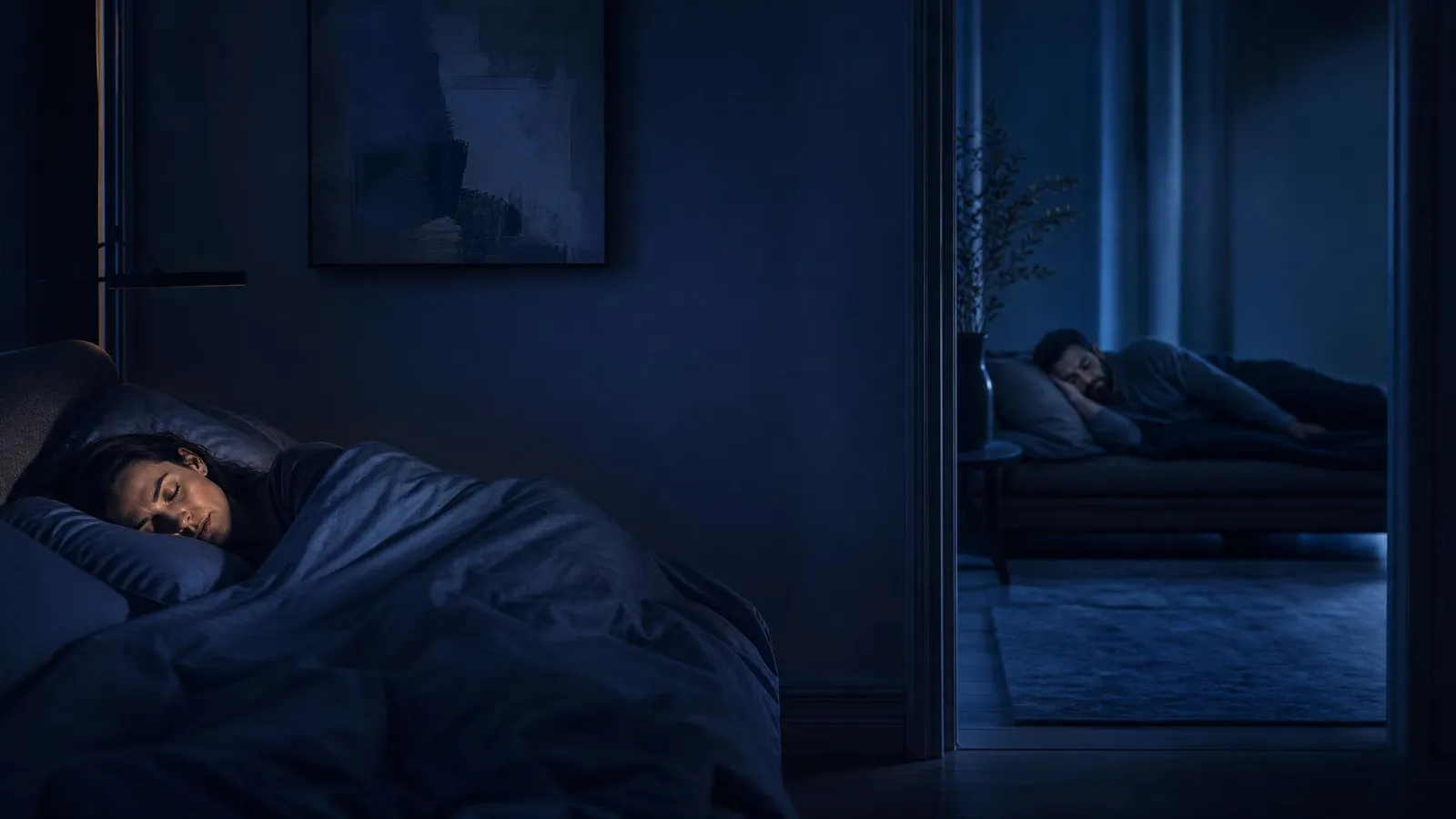A couple sleeping separately at night — a woman asleep in the bedroom while her partner sleeps in another room seen through an open doorway, illustrating the sleep divorce trend.
